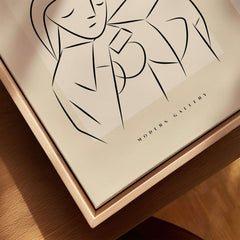 Picasso Abstract Couple Lovers Embrace Line Art Figures Poster Modern Gallery Wall Art on a wooden surface.