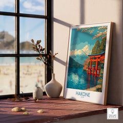 Hakone Wall Art Japan Red Torii Gate Poster displayed on a wooden table near a window with a serene landscape.