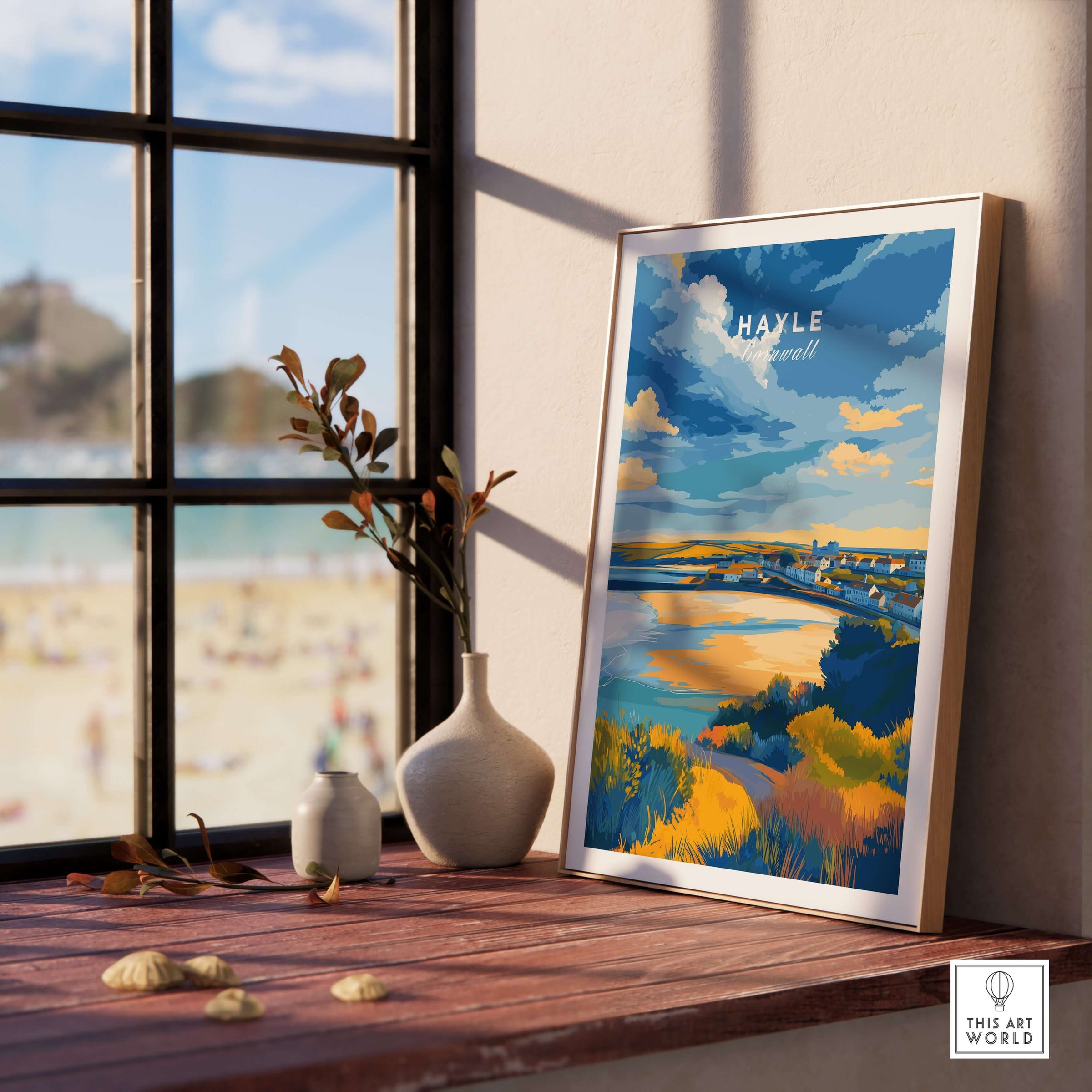 Hayle Cornwall Poster - UK Coastal Landscape Print displayed on a wooden table beside a window with beach views.