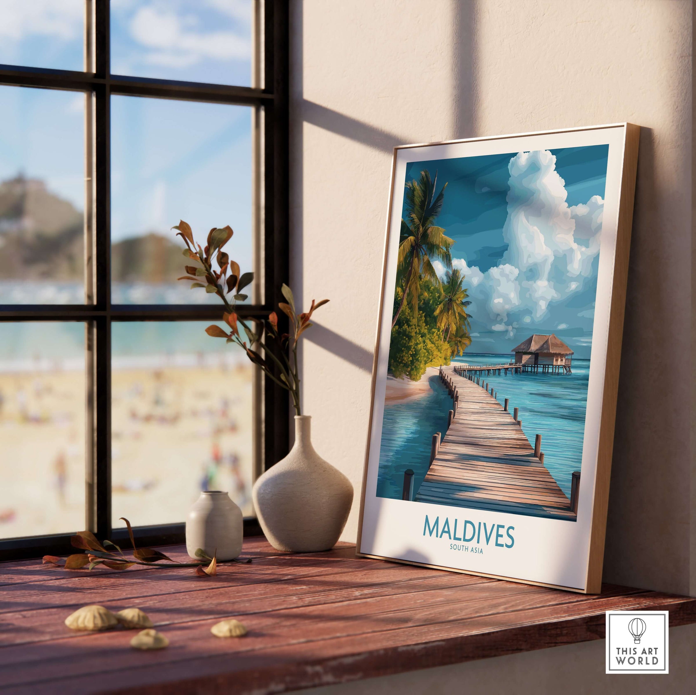 Maldives Wall Art Print - Beach displayed on a wooden table beside a window overlooking a sandy beach.