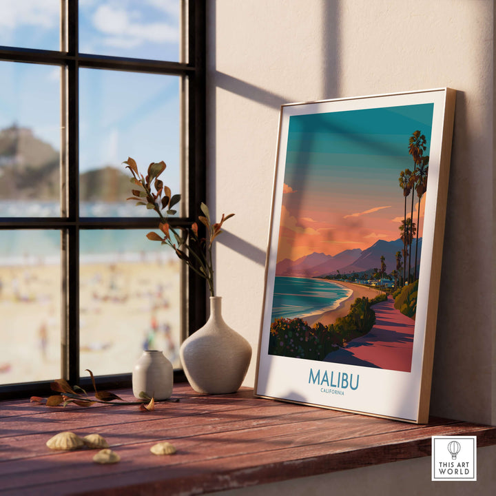 Framed Malibu California beach sunset poster on a wooden table near a window, capturing coastal beauty.