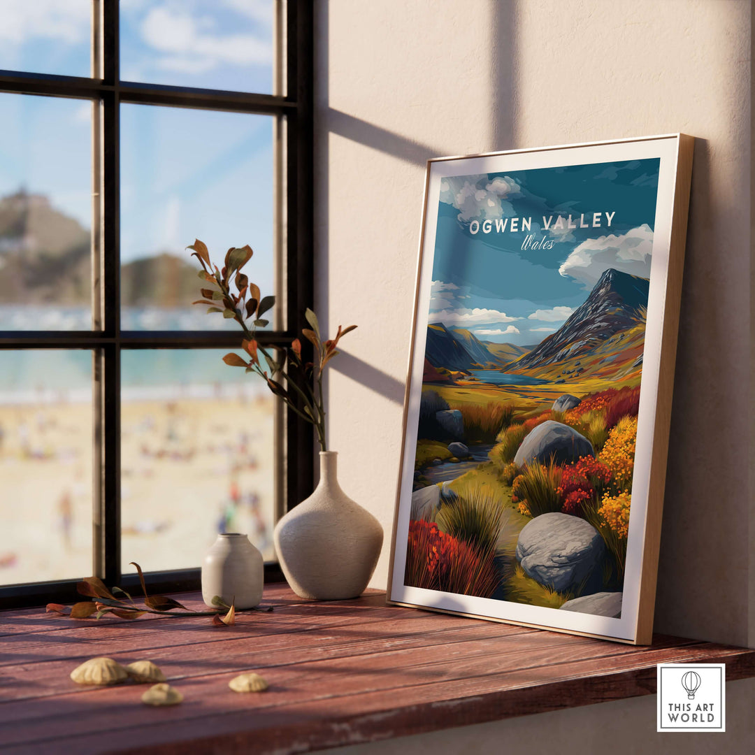 Ogwen Valley Wales poster in a sunlit room with a window view, showcasing vibrant landscape art featuring mountains and colorful foliage.