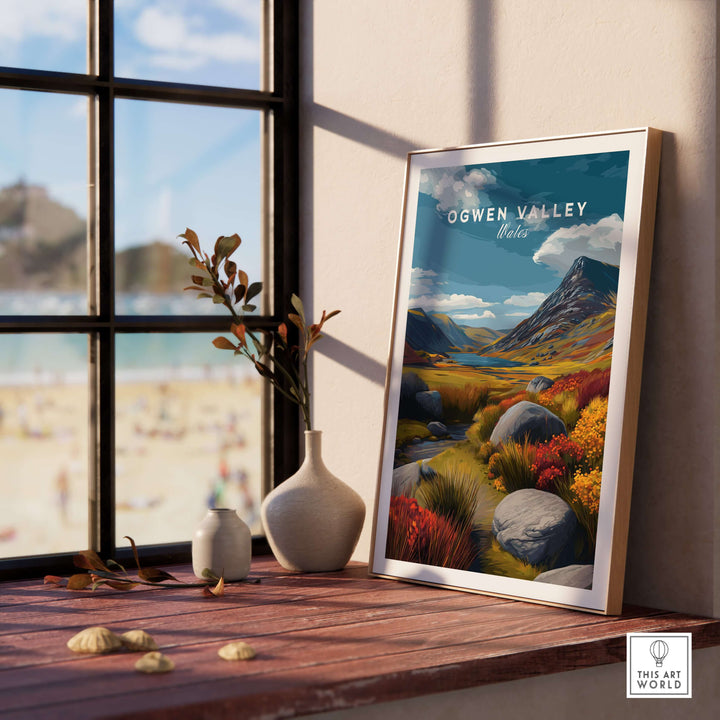 Ogwen Valley Wales poster in a sunlit room with a window view, showcasing vibrant landscape art featuring mountains and colorful foliage.