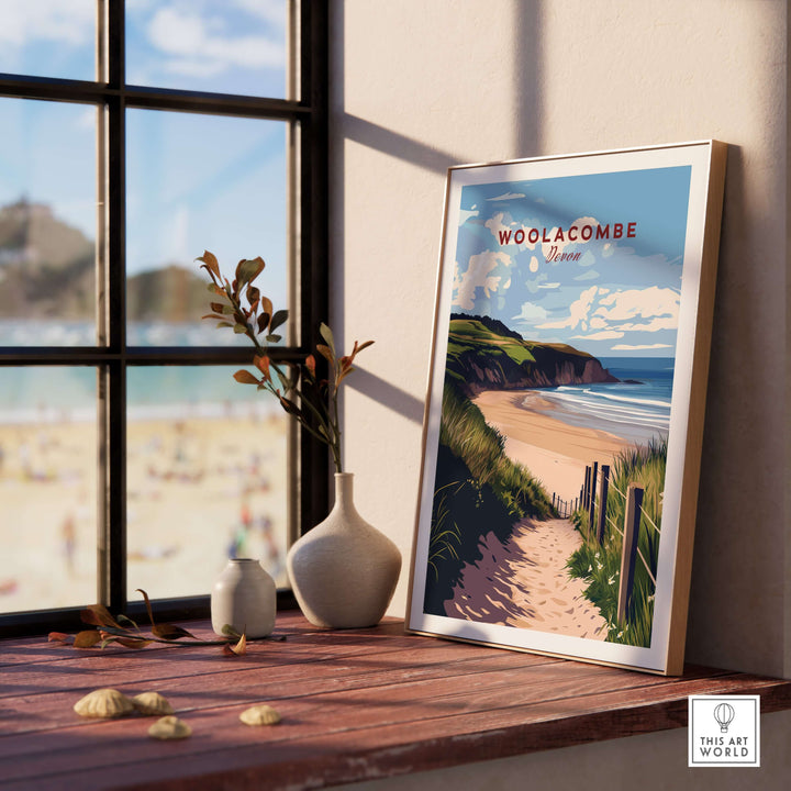Woolacombe Beach Path Print framed decor on a table, showcasing coastal Devon scenery and tranquil beach vibes.