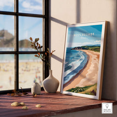 Woolacombe Devon Long Beach Sunset Poster - Rolling Waves Print displayed on a wooden table by a window.