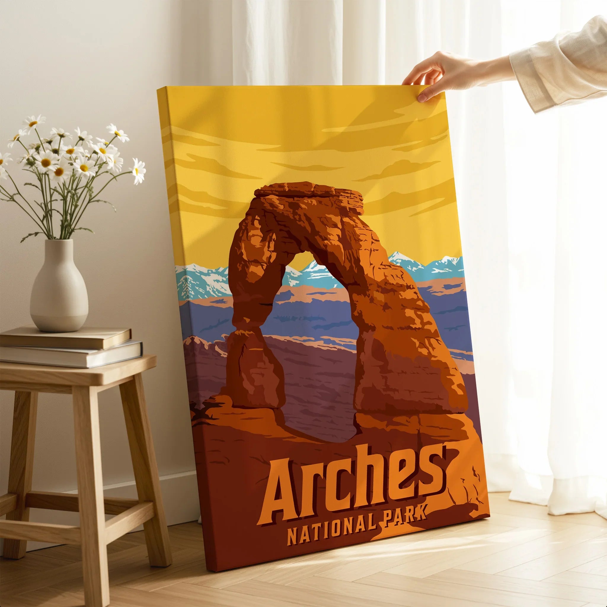 Person holding Arches National Park canvas print by a window, with desert landscape artwork.