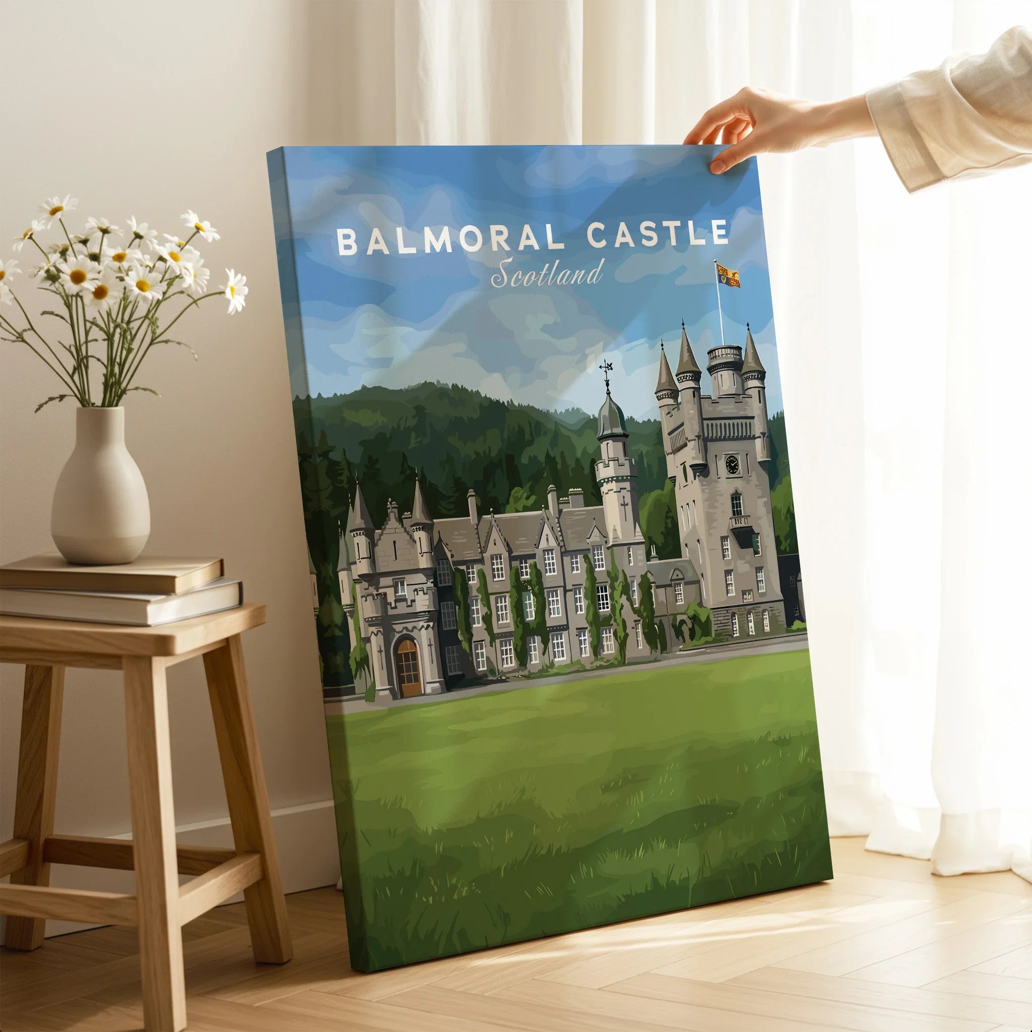 Hand holding Balmoral Castle Scotland travel poster canvas in bright living room setting