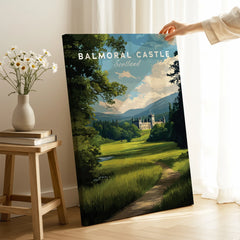 Hand holding Balmoral Castle Scotland travel poster canvas print in modern room with books and flowers