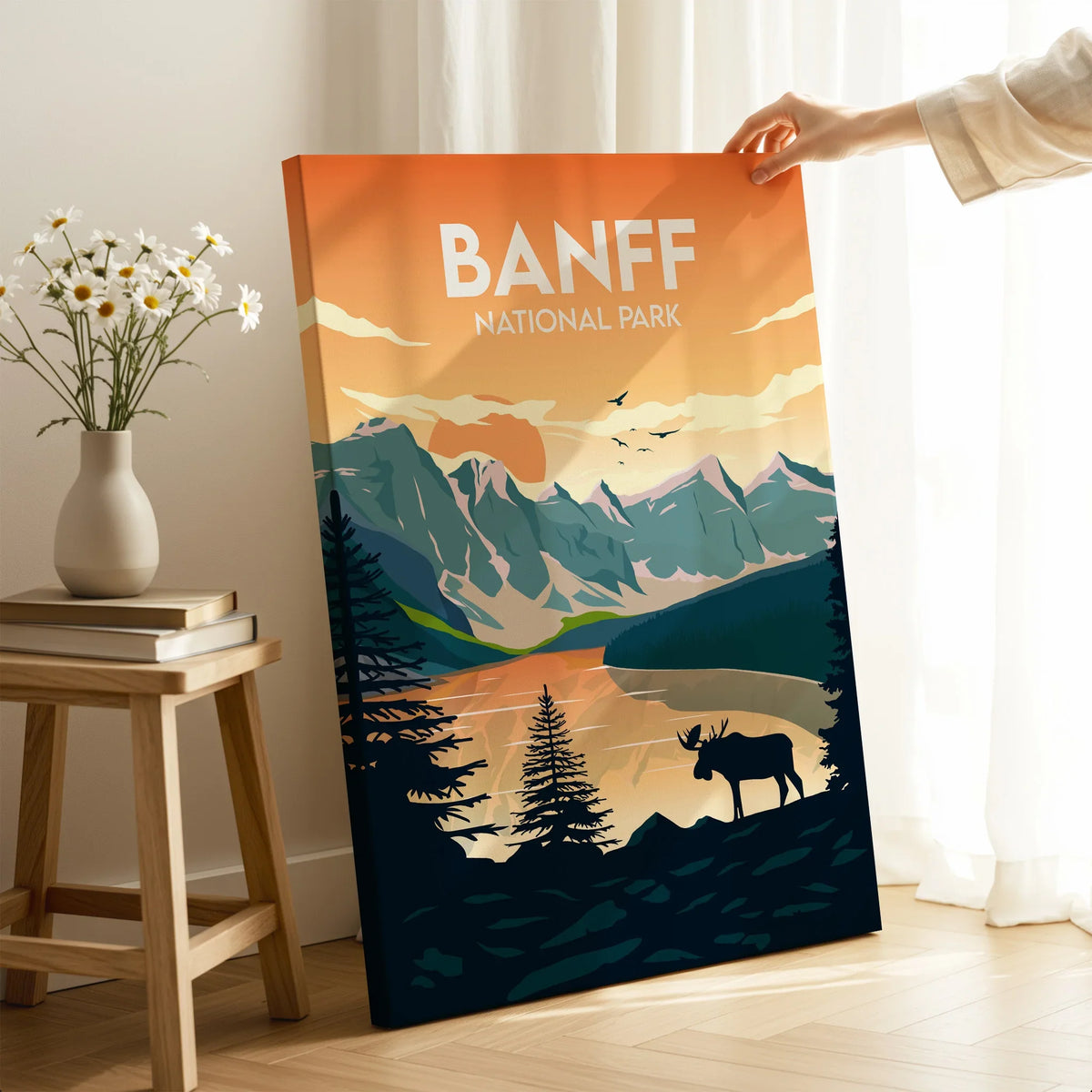 Banff National Park print with sunset mountains and moose, hand holding canvas in cozy room
