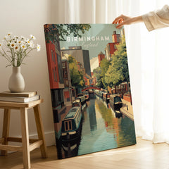 Hand holding Birmingham England travel poster canvas print with city canal scene in modern room