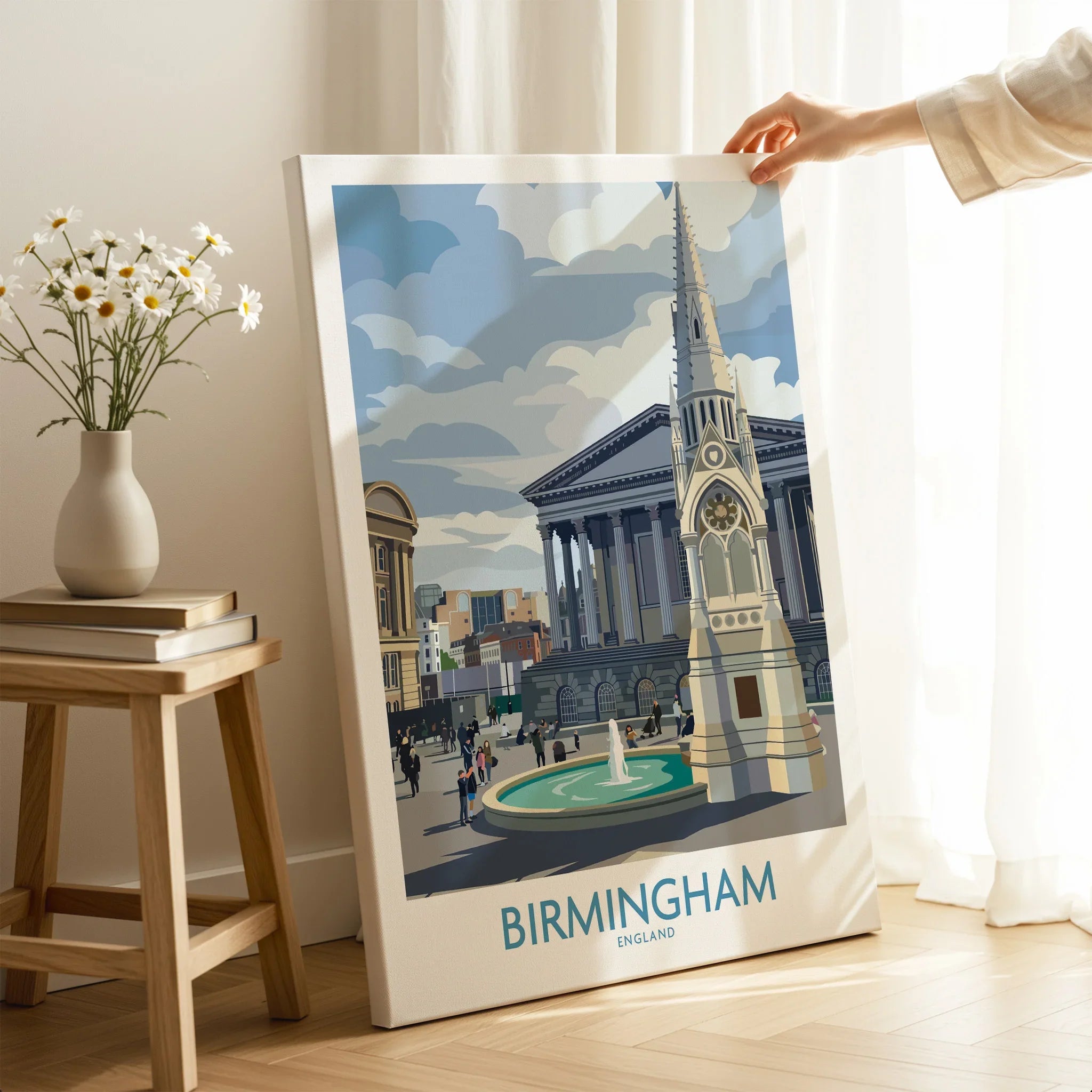 Hand holding Birmingham city travel poster canvas print in modern room with flowers and books