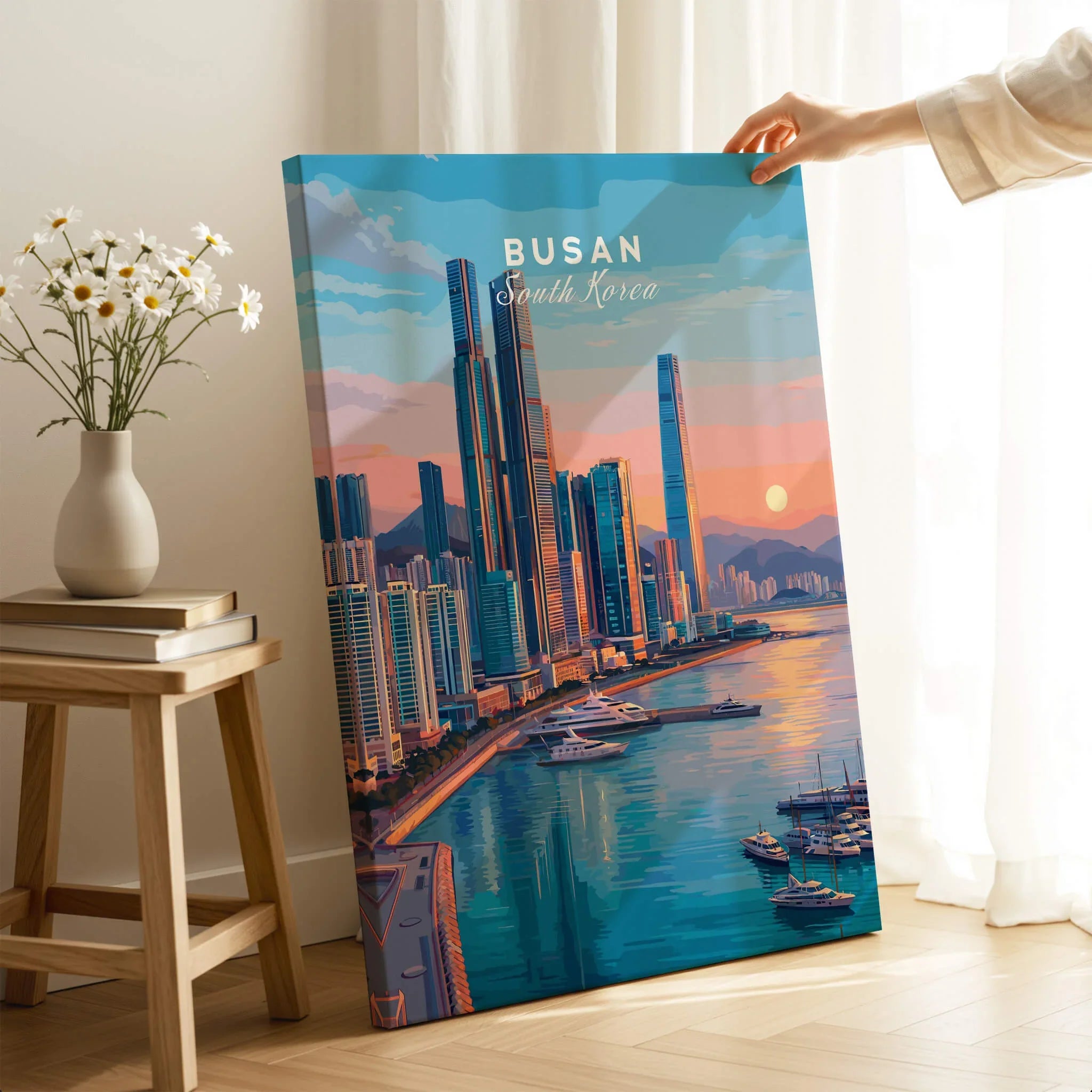 Hand holding Busan city wall art print with colorful skyline and waterfront in modern room