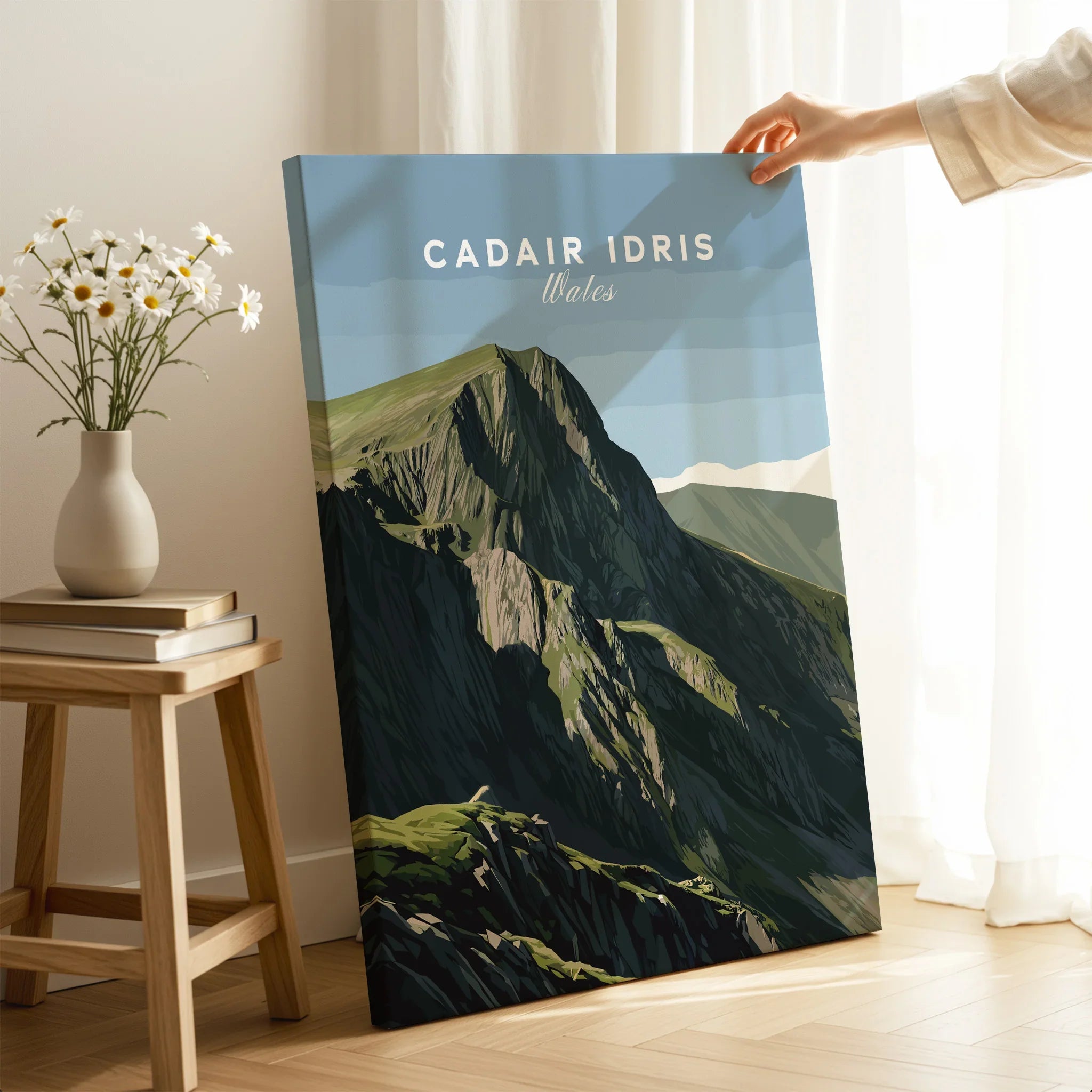 Hand holding canvas print of Cadair Idris Wales mountain art in cozy room with sunlight.