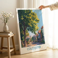 Colchester England travel poster canvas print with tree-lined street, hand holding artwork in cozy room setting