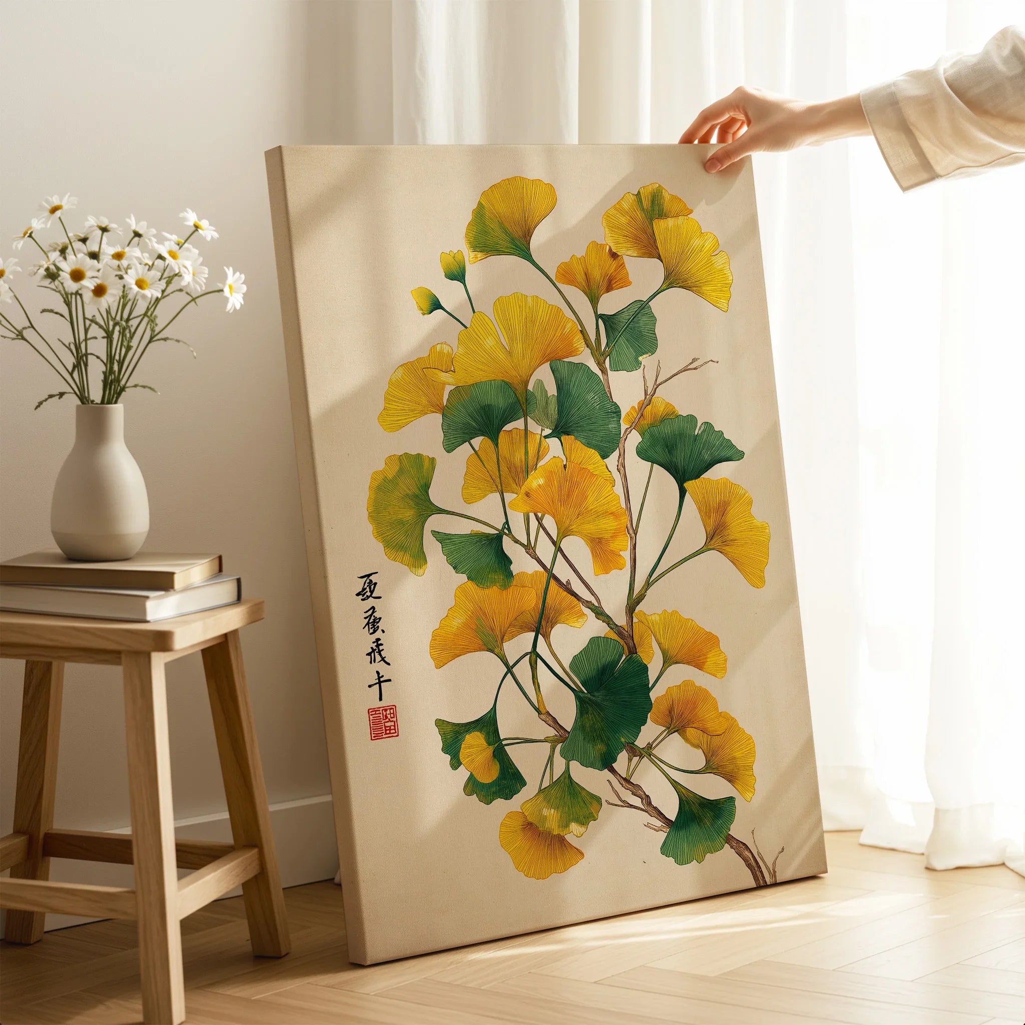 Hand holding canvas print with yellow ginkgo leaves in modern room, wall art decor