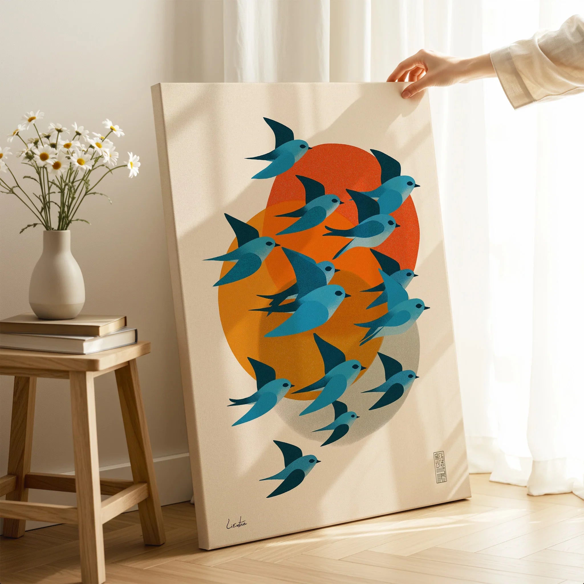 Modern canvas wall art with blue birds in flight and orange sun, displayed in bright room