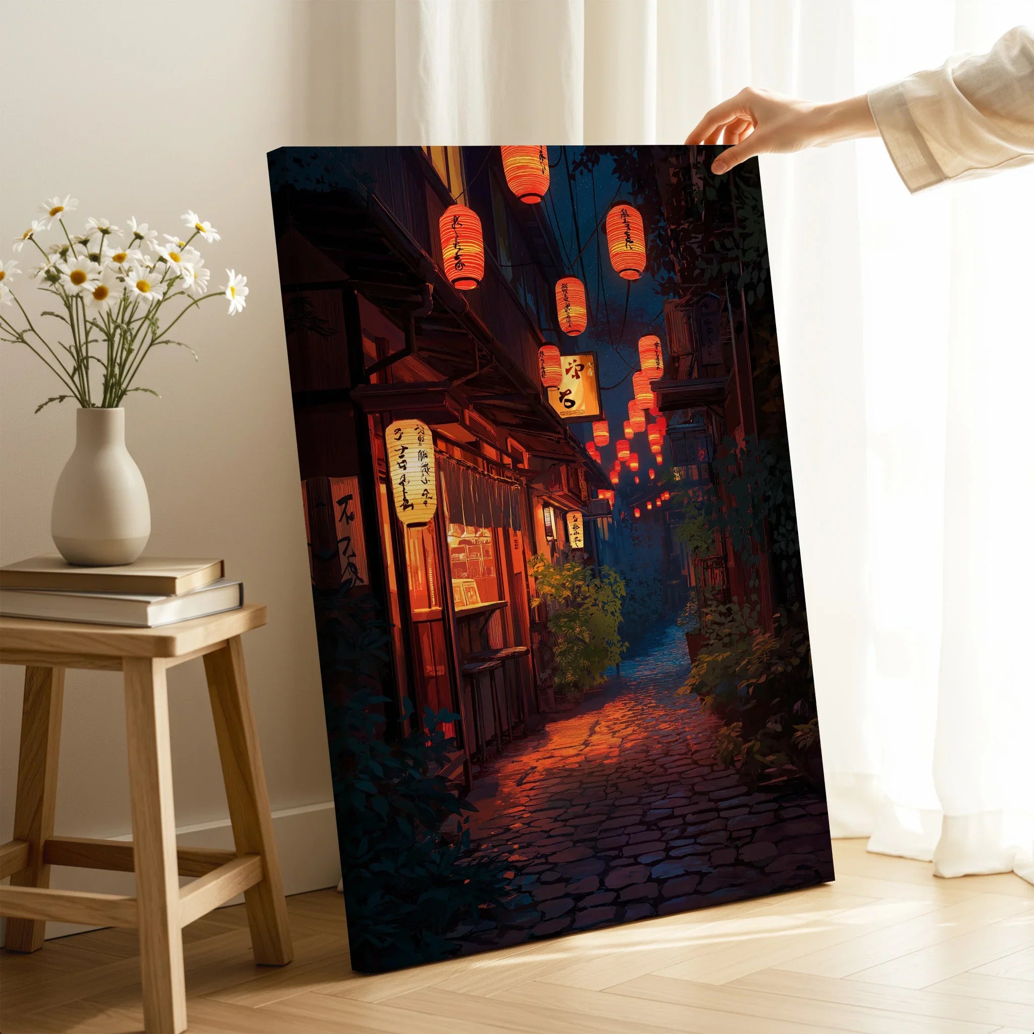 Hand holding Japanese street art canvas print with lanterns in cozy room setting