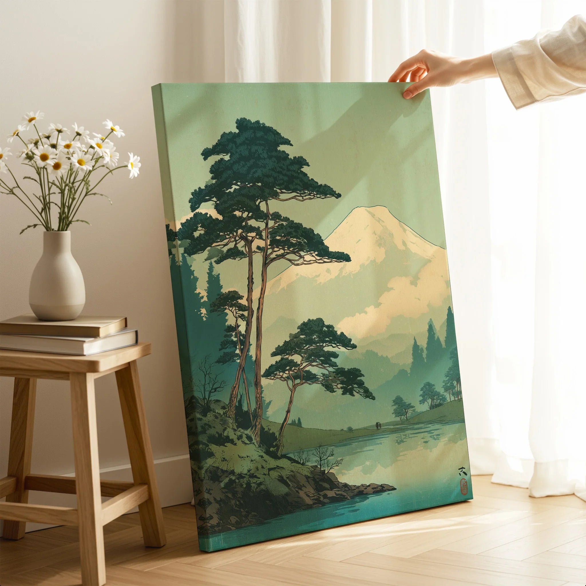 Hand holding Japanese woodblock style mountain landscape canvas print in cozy room