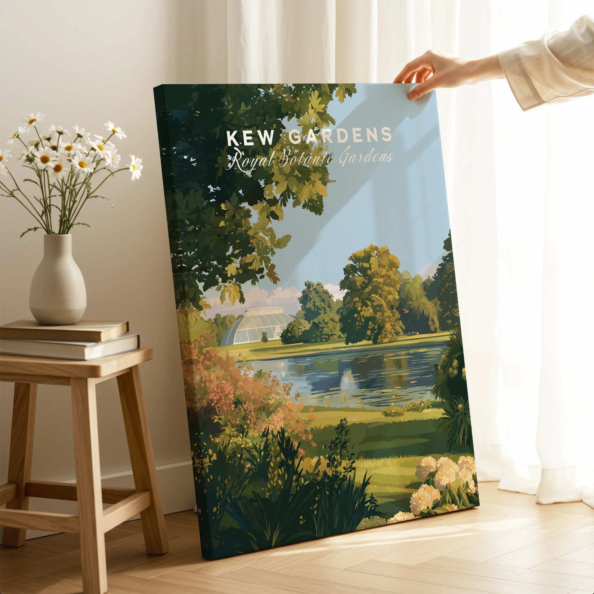 Hand holding Kew Gardens canvas art print in bright room, floral vase on stool nearby