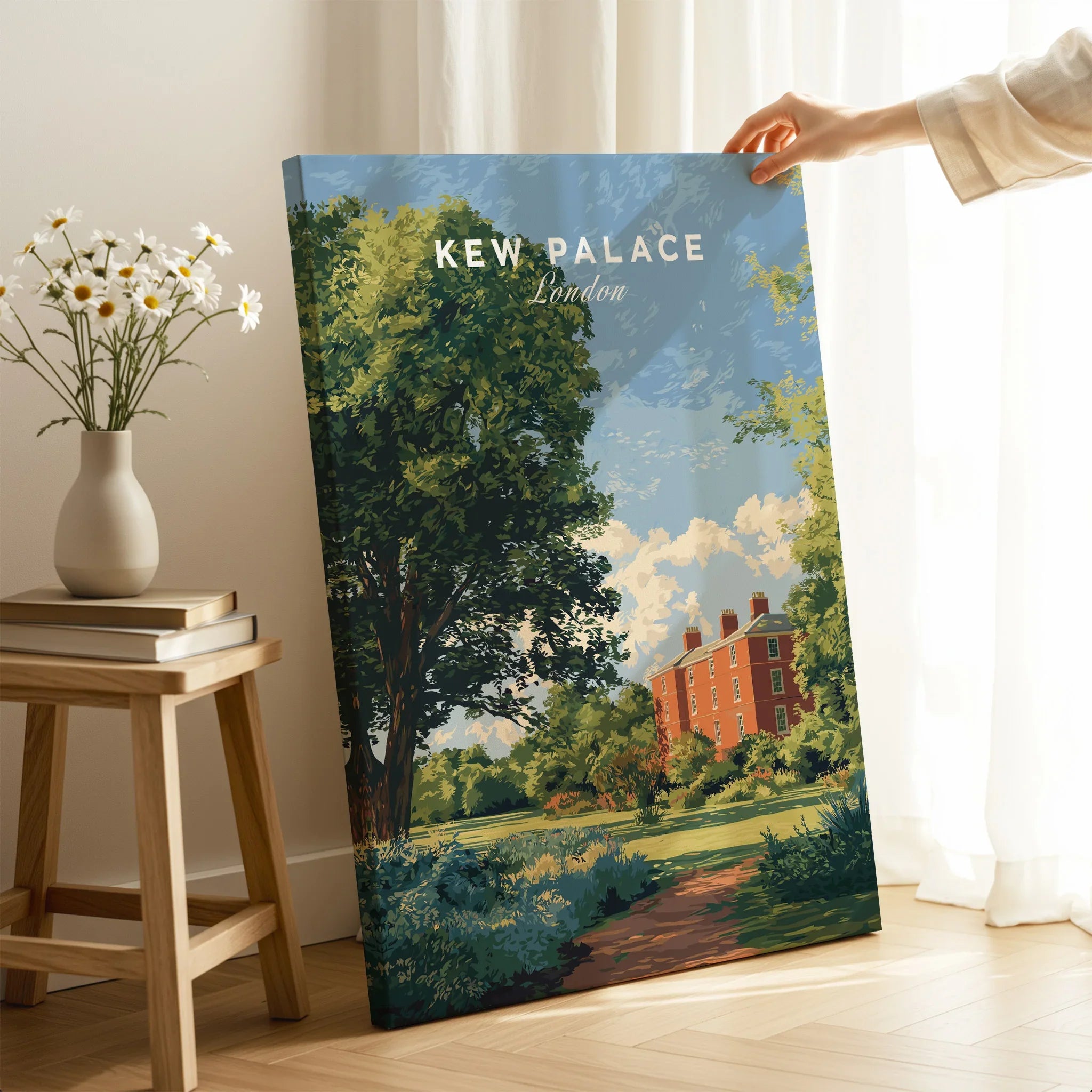Hand holding Kew Palace London travel poster print in sunlit room with books and daisy vase