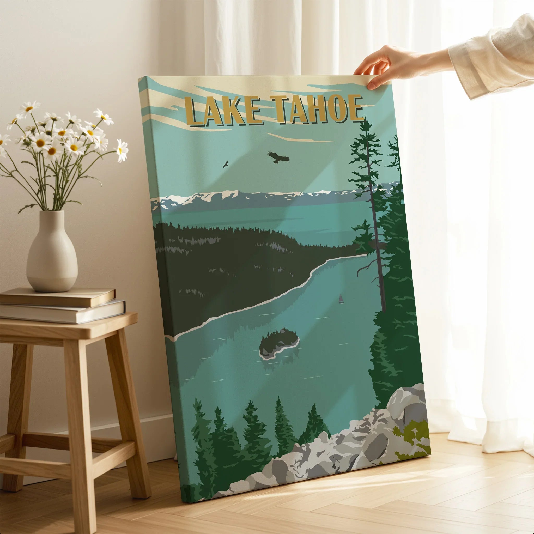 Hand holding Lake Tahoe canvas print with retro travel poster design in a cozy room setting
