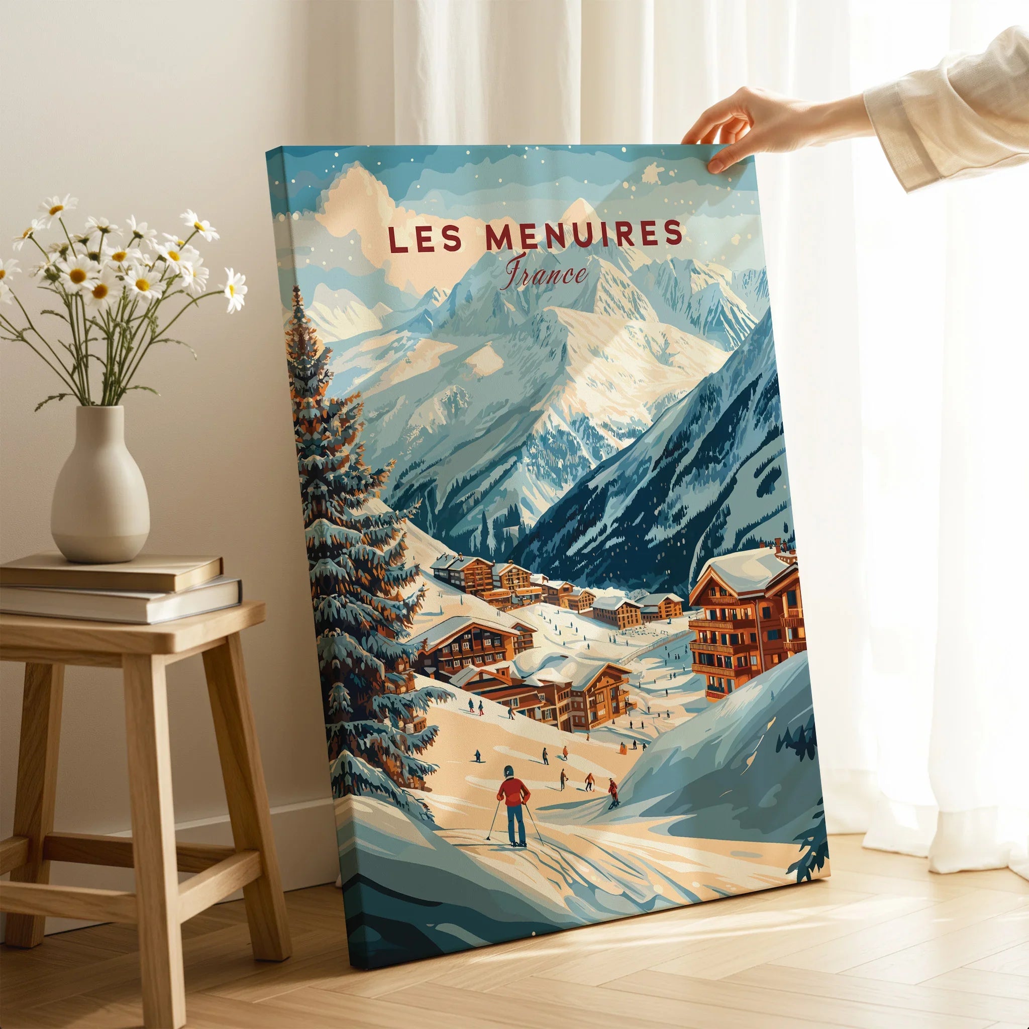 Hand holding Les Menuires France ski resort art print with snowy mountains and village.
