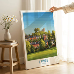 Lewes England travel poster canvas print with colorful town illustration, hand holding edge in cozy room setting.