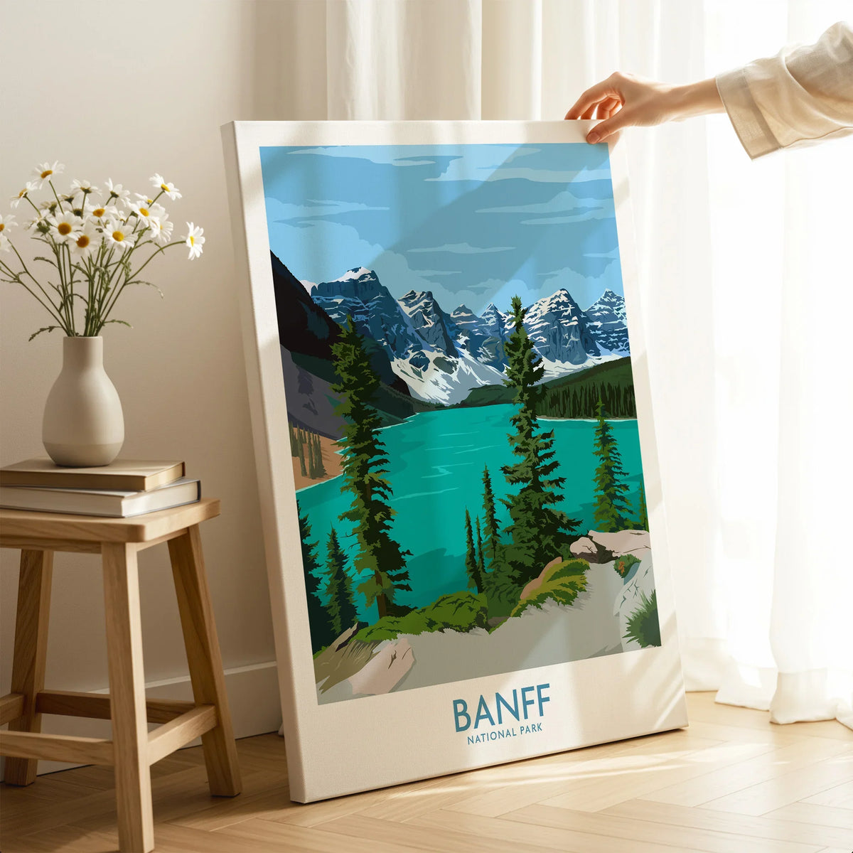 Hand holding Banff National Park canvas print in a modern room with sunlight and flowers