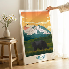Hand holding Denali National Park canvas print with bear and mountain landscape in cozy room