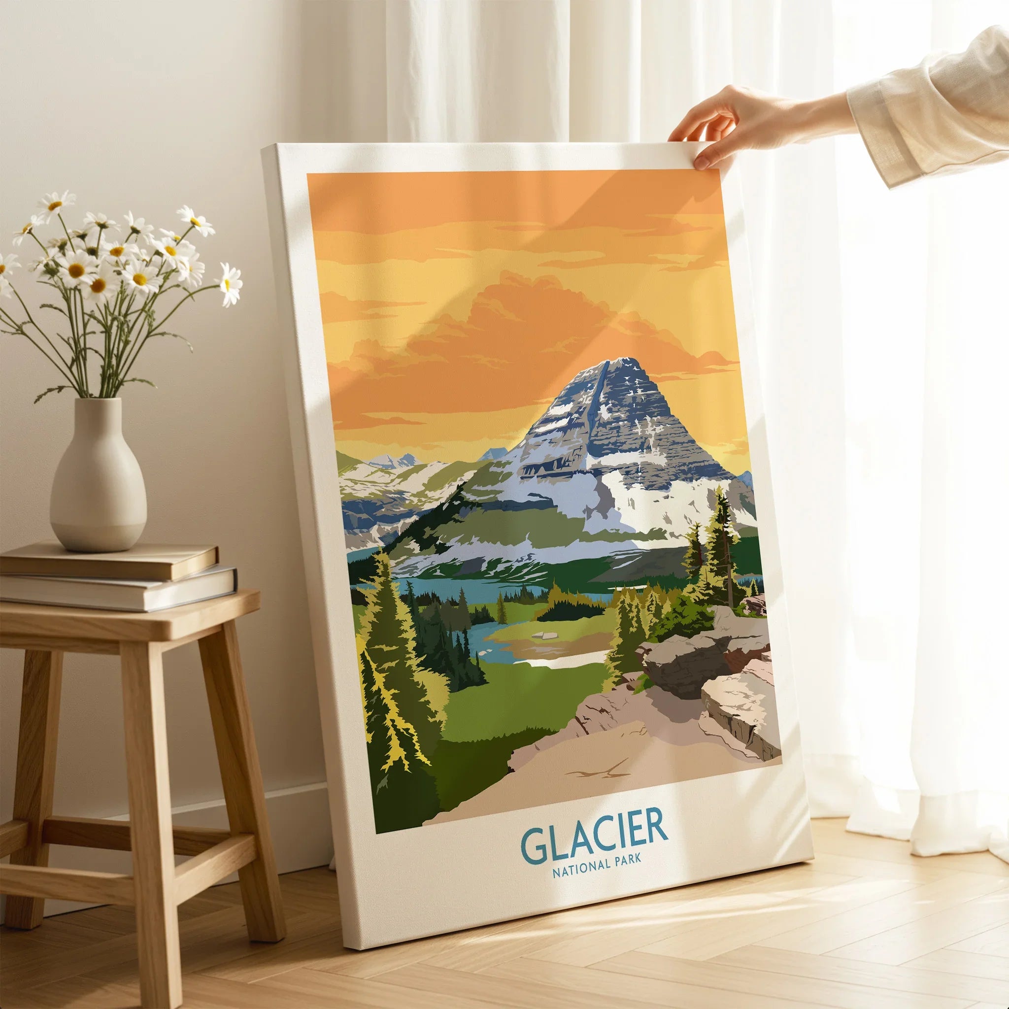 Hand holding Glacier National Park canvas print with mountain landscape in sunny room