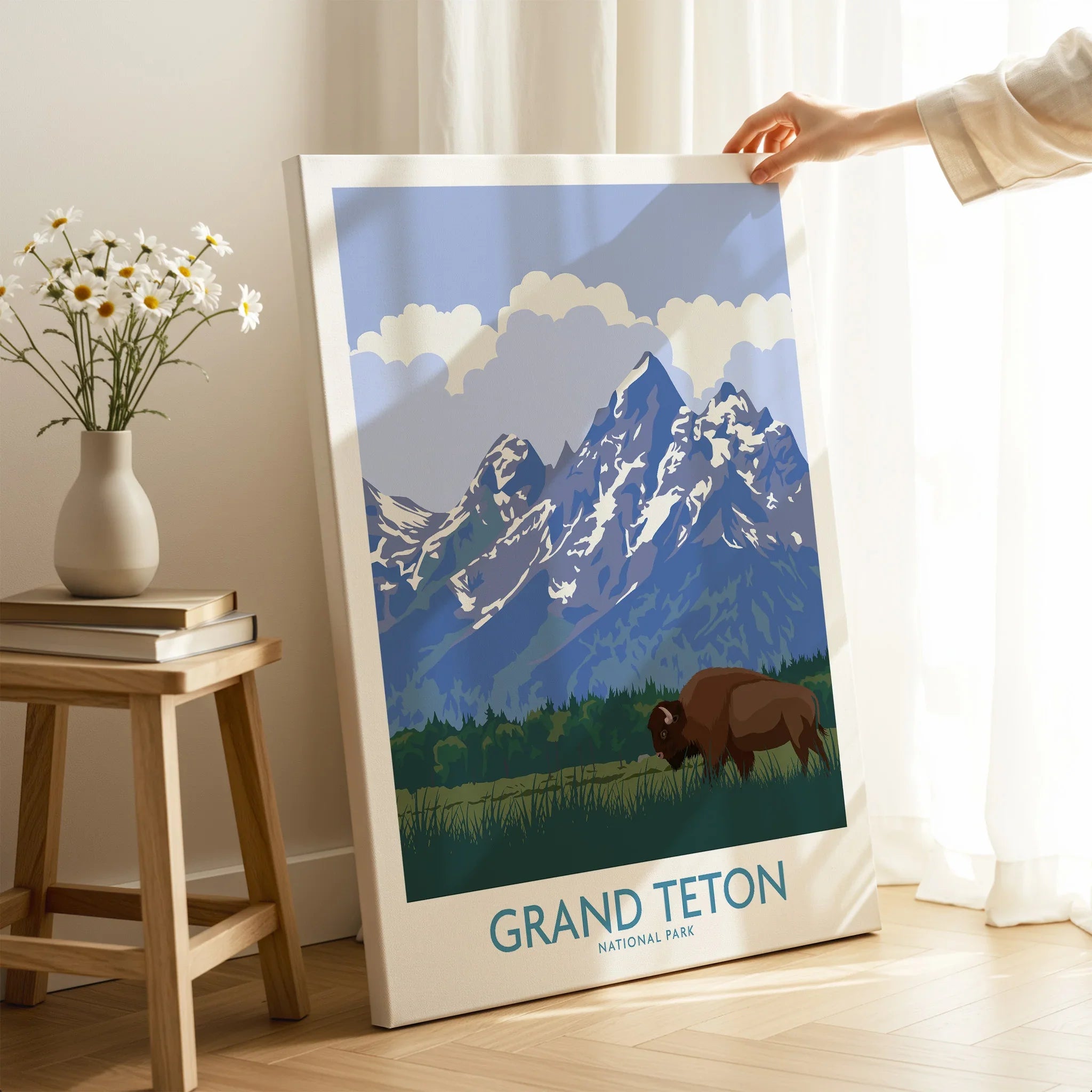 Hand holding Grand Teton National Park canvas print with bison and mountains in sunlit room
