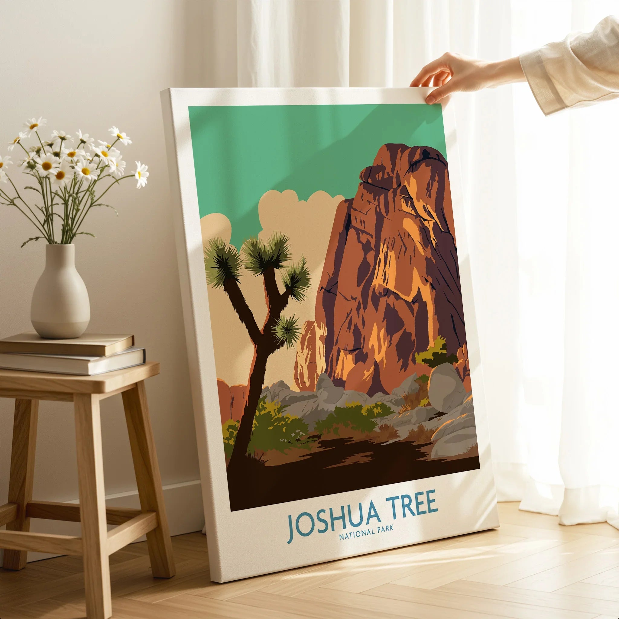Hand holding Joshua Tree National Park canvas print in cozy room with sunlight and flowers