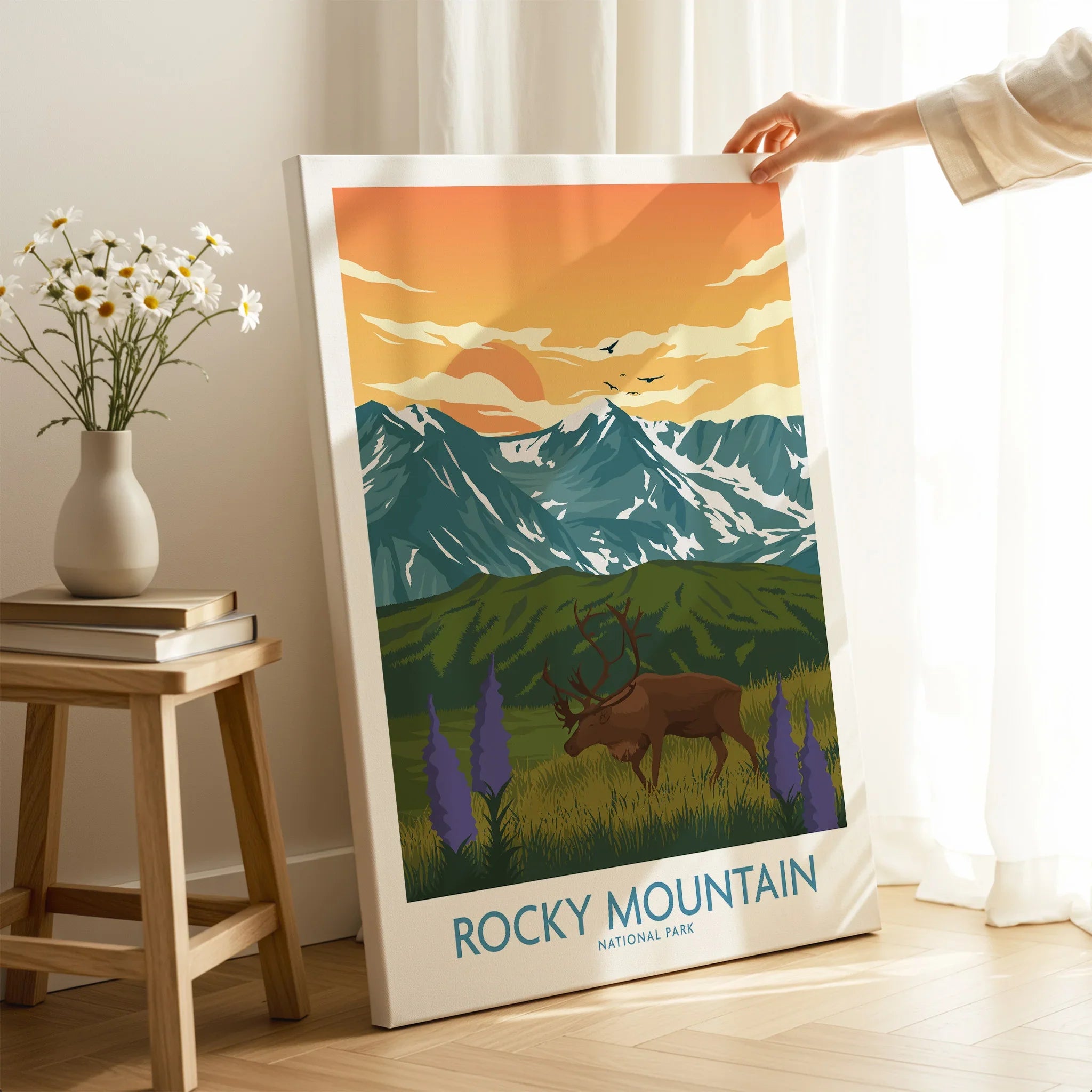 Hand holding Rocky Mountain National Park canvas print with elk and mountain art in room