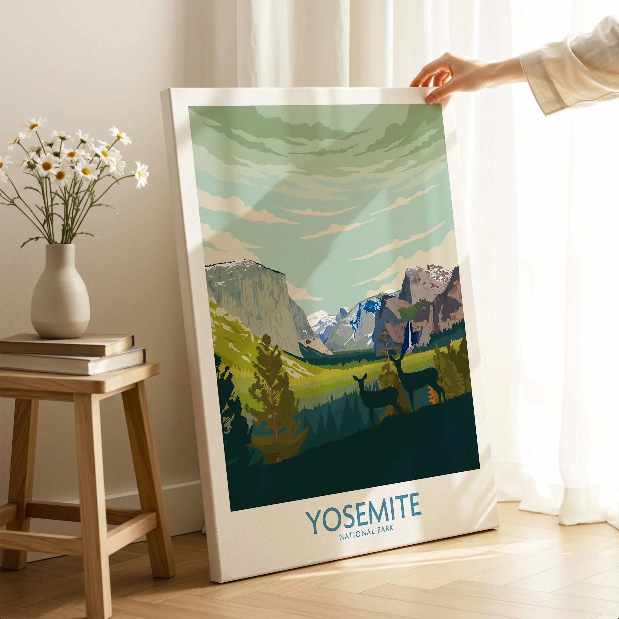 Hand holding Yosemite National Park canvas print with mountain landscape in bright room.