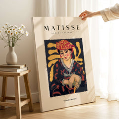 Matisse Art Prints - Woman in Patterned Hat & Dress Poster featuring a colorful art print in a gallery setting.