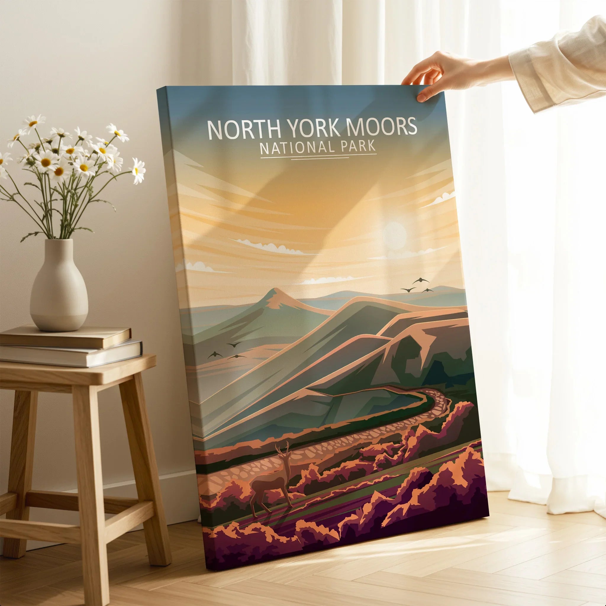 Hand holding North York Moors National Park travel poster in bright, modern room