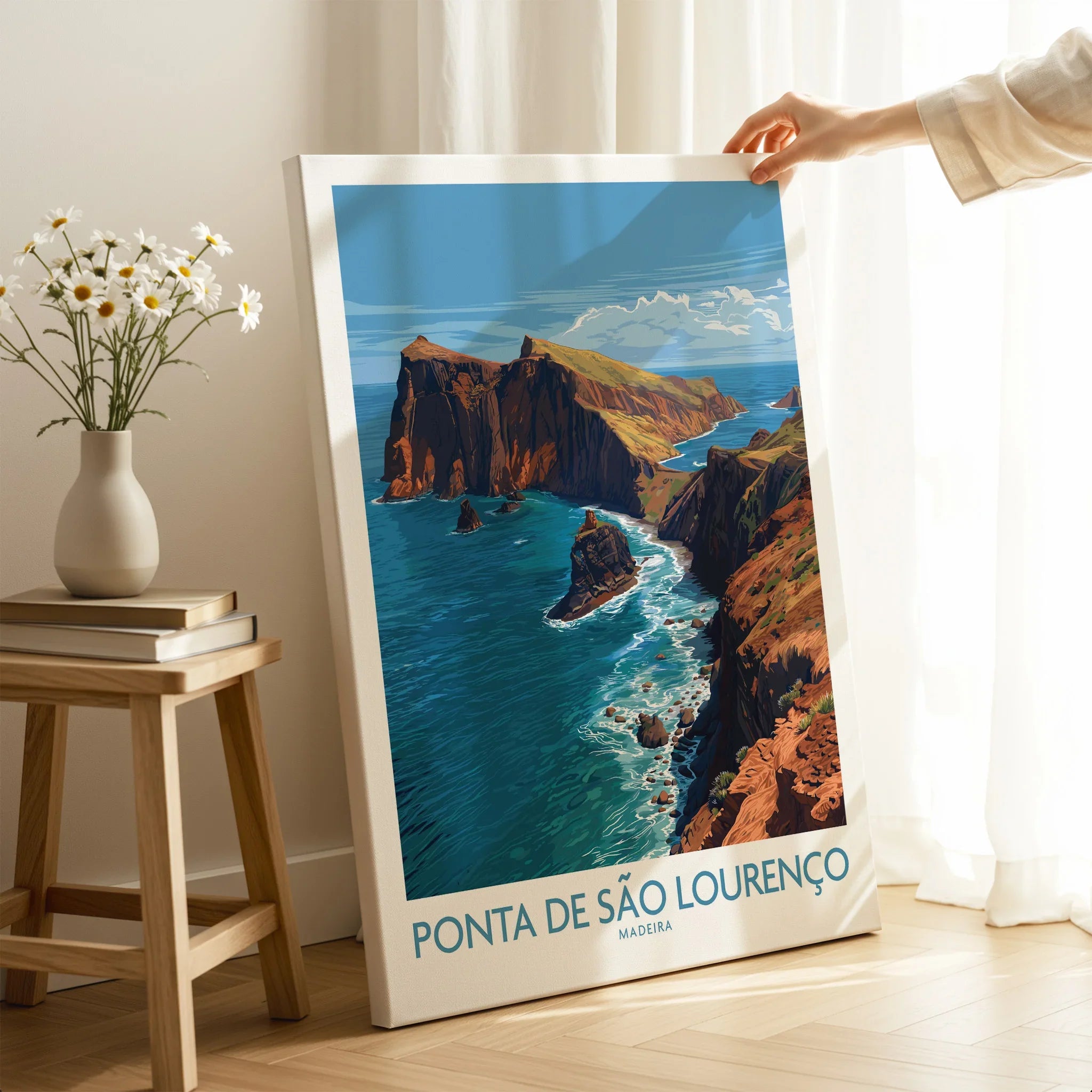 Hand holding Ponta de São Lourenço Madeira travel poster in bright modern room with coastal cliffs art
