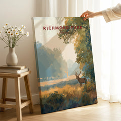 Hand holding a Richmond Park travel poster canvas print with deer and trees in a modern room