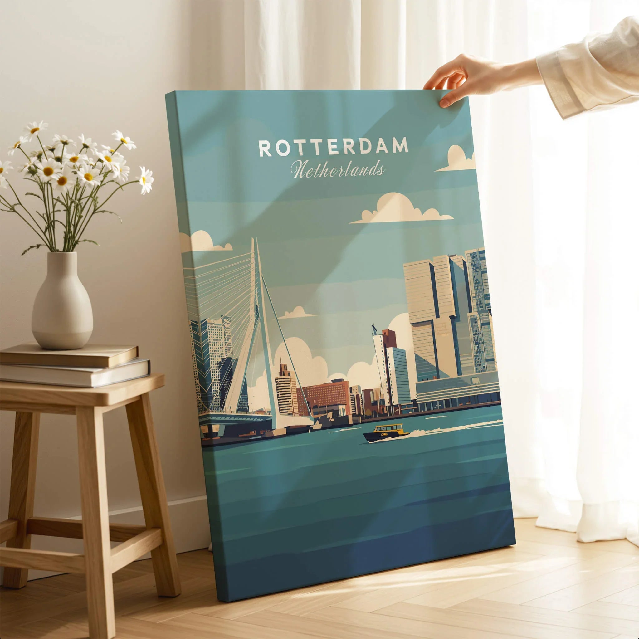 Hand holding Rotterdam city skyline canvas print in modern living room setting with flowers and books