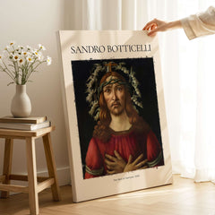 Botticelli Man of Sorrows Christ Art Print Religious Renaissance Painting Poster displayed in a bright setting with flowers.