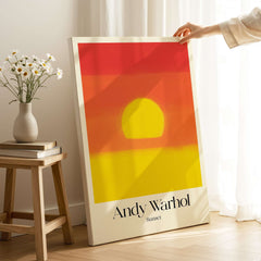 Andy Warhol Sunset Red Yellow Pop Art Abstract Print Modern Landscape Poster displayed indoors with a vase and flowers.