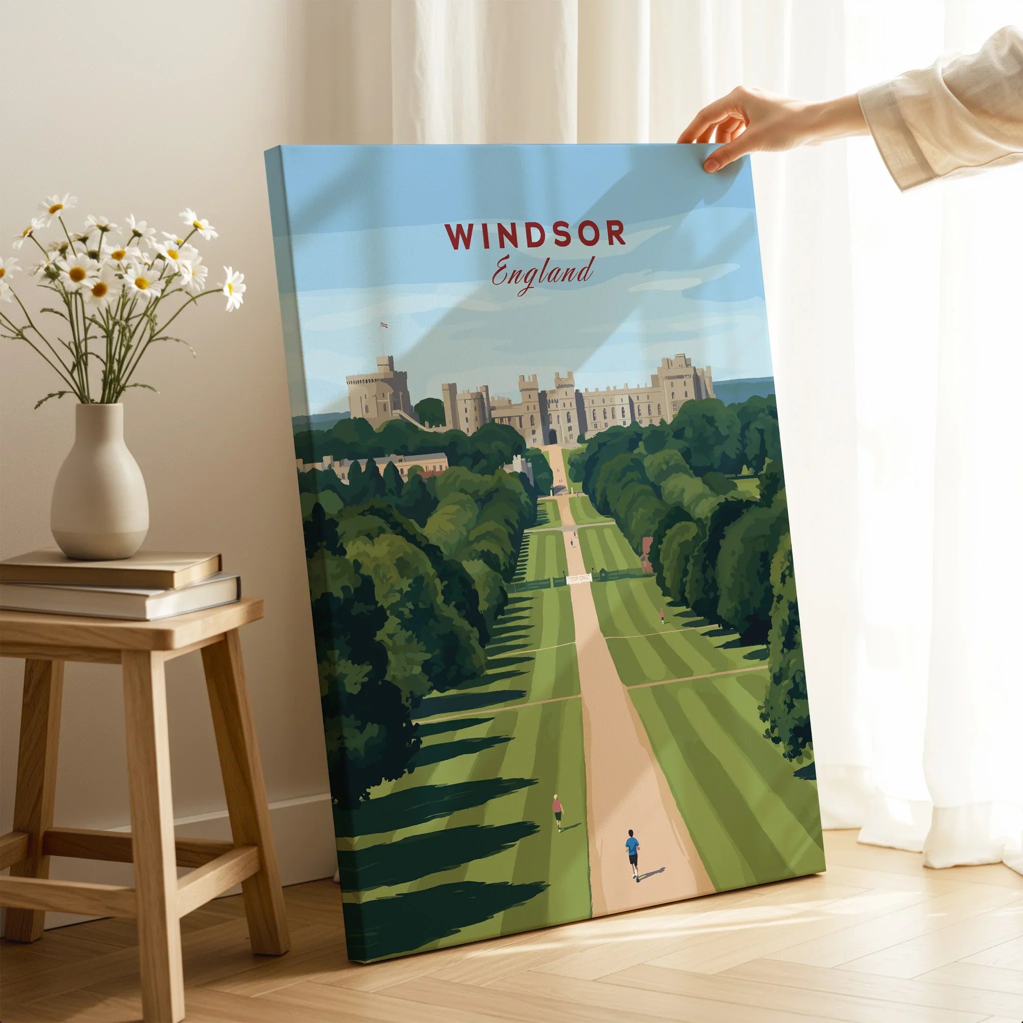 Hand holding Windsor England travel poster canvas print in cozy room with flowers and books