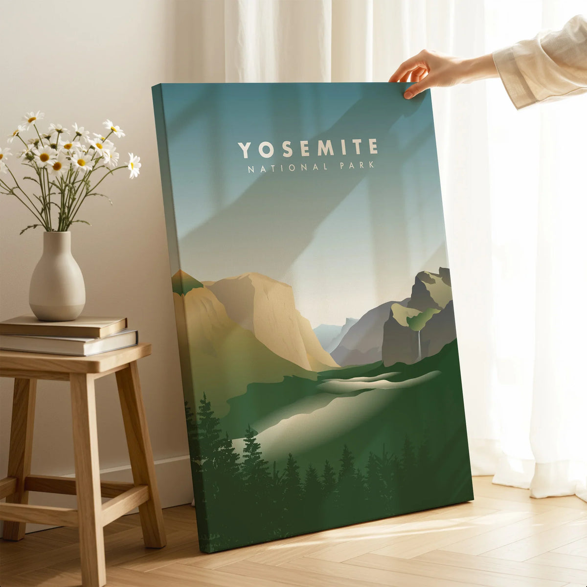 Hand holding Yosemite National Park canvas print in modern room with sunlight and flowers