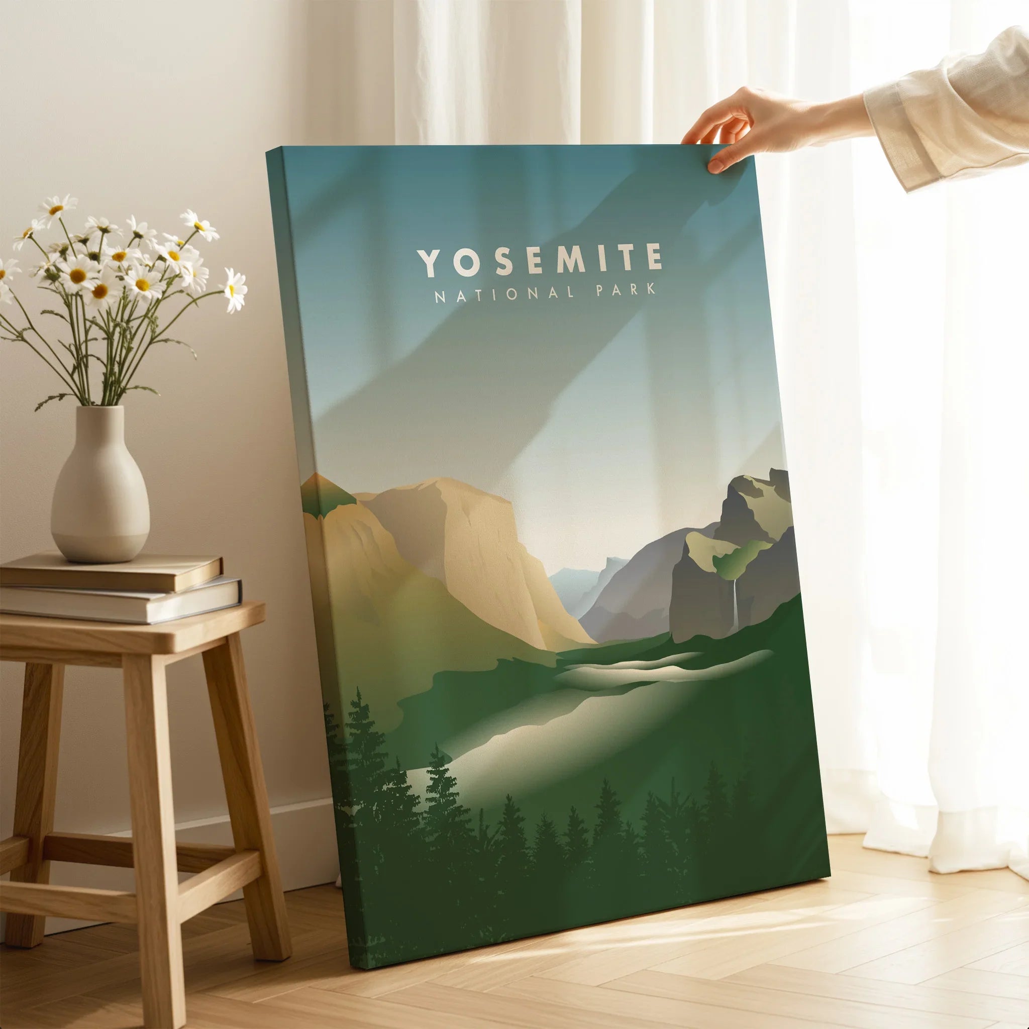 Hand holding Yosemite National Park canvas print in modern room with sunlight and flowers