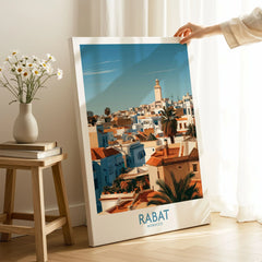 Rabat Morocco Minaret Skyline Wall Art — medina rooftops and a pale minaret in late afternoon sun, shown as canvas print mirror edge hand holding room setting