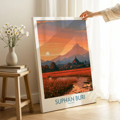 Suphan Buri Thailand Temple Sunset Wall Art — a lotus-covered lake and temple spire at sunset beneath a mountain peak, shown as canvas print mirror edge hand holding room setting