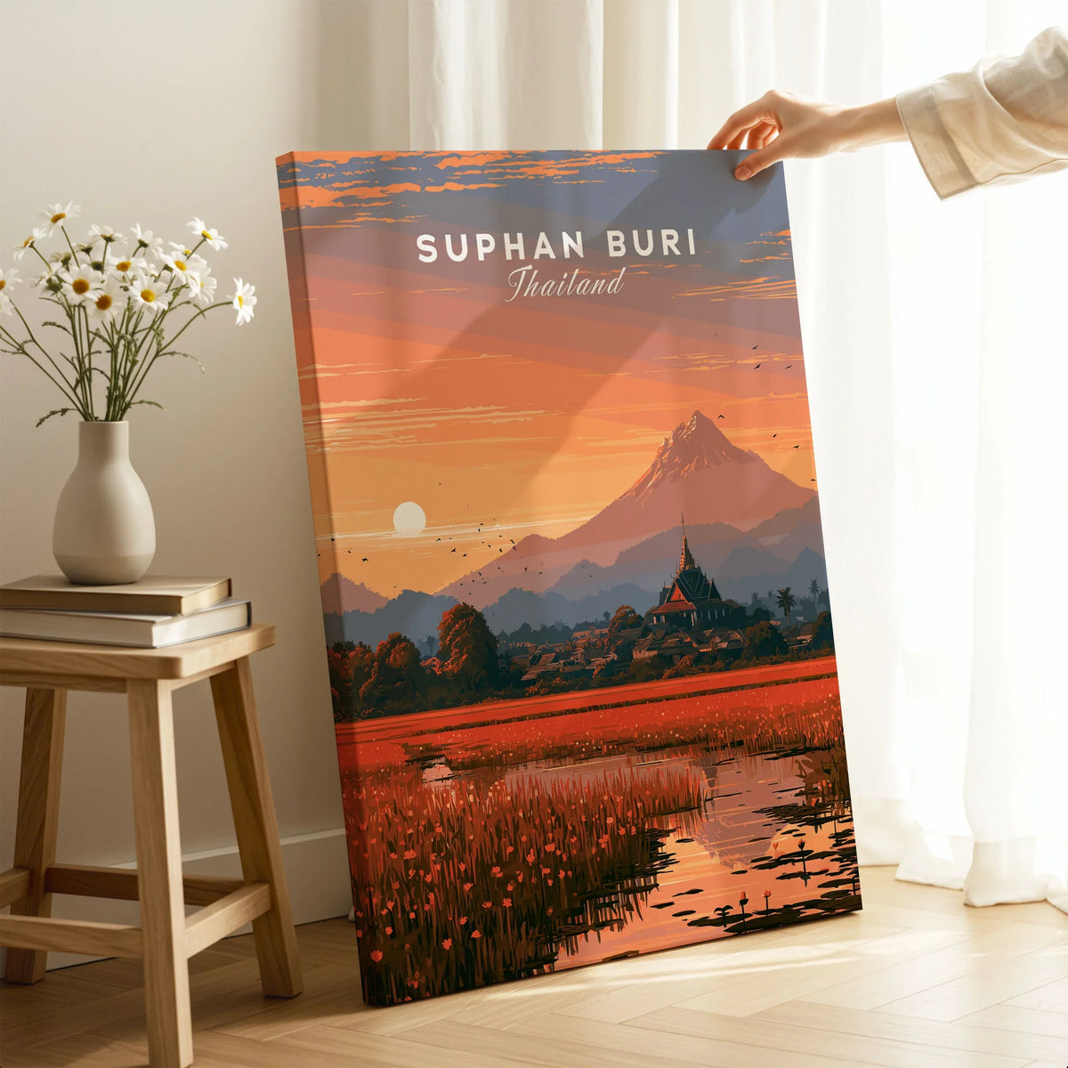 Suphan Buri Thailand Lotus Lake Travel Poster — a lotus-covered lake and temple spire at sunset beneath a mountain peak, shown as canvas print mirror edge hand holding room setting