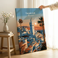 Tangier Morocco Sunset Medina Travel Poster — Tangier medina rooftops and a minaret above a bay dotted with sails, shown as canvas print mirror edge hand holding room setting