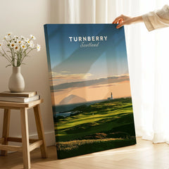 Turnberry Scotland Ailsa Craig Travel Poster — Ailsa Craig and the white lighthouse across rolling coastal turf at dusk, shown as canvas print mirror edge hand holding room setting