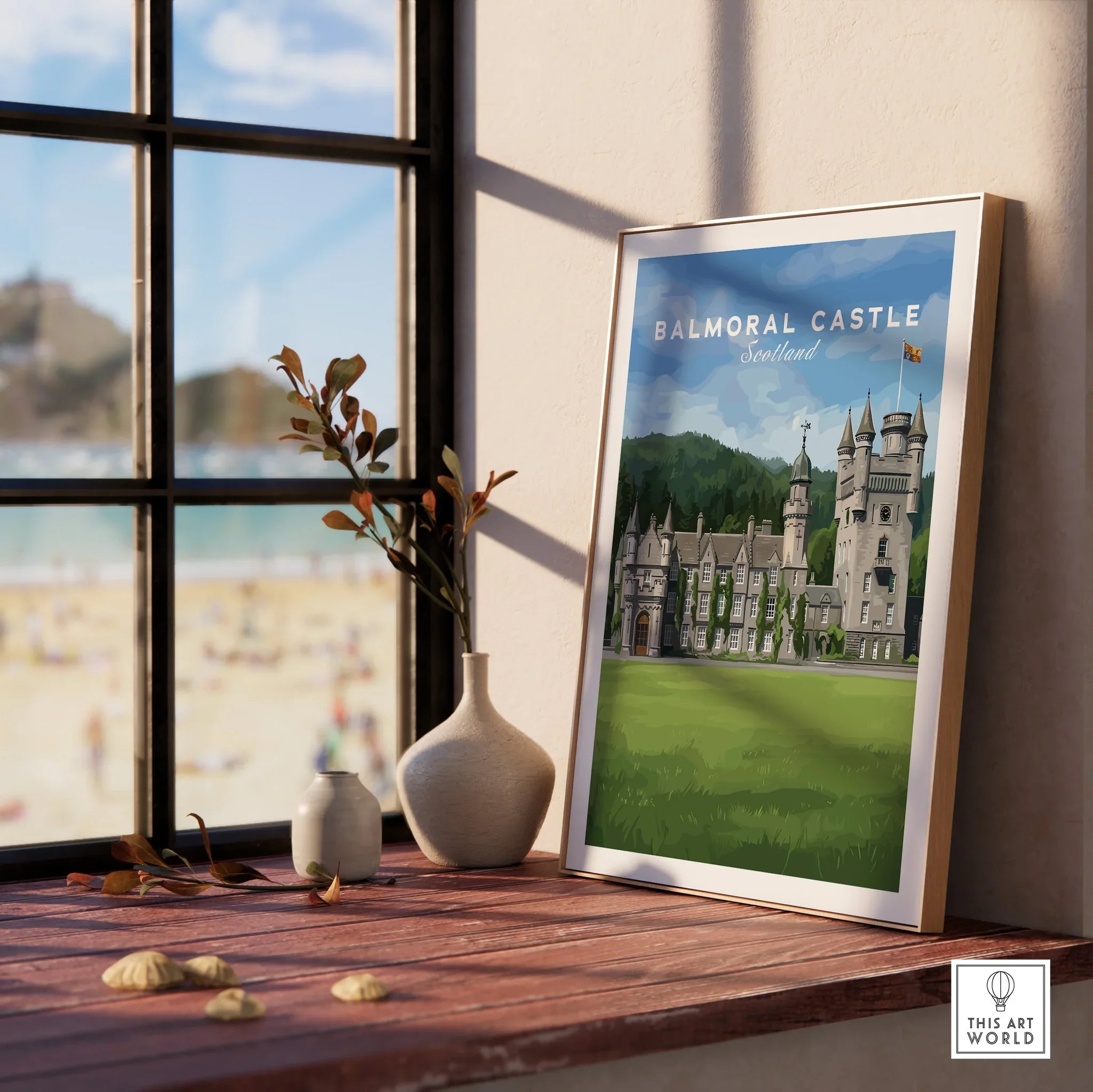 Framed Balmoral Castle Scotland travel poster on a windowsill with vases and beach view